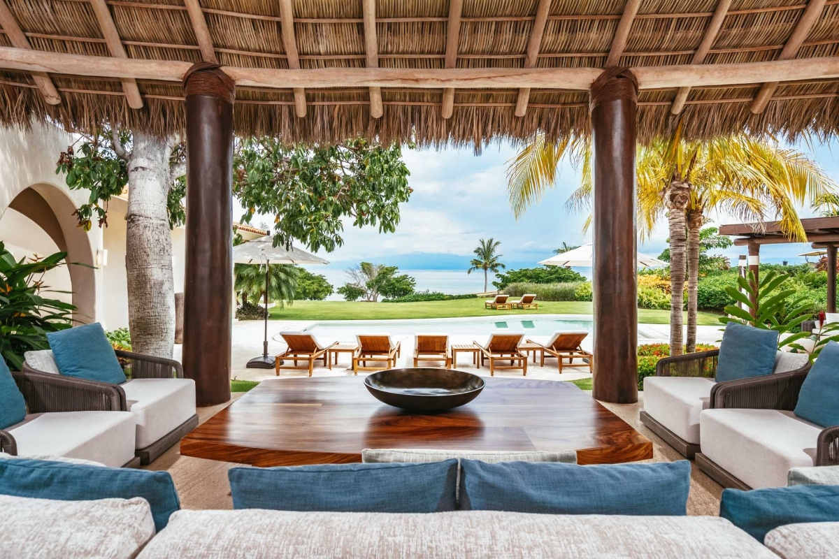 Open-air living room at Casa Caída de Agua with wood-beamed ceilings, designer furniture, and ocean views