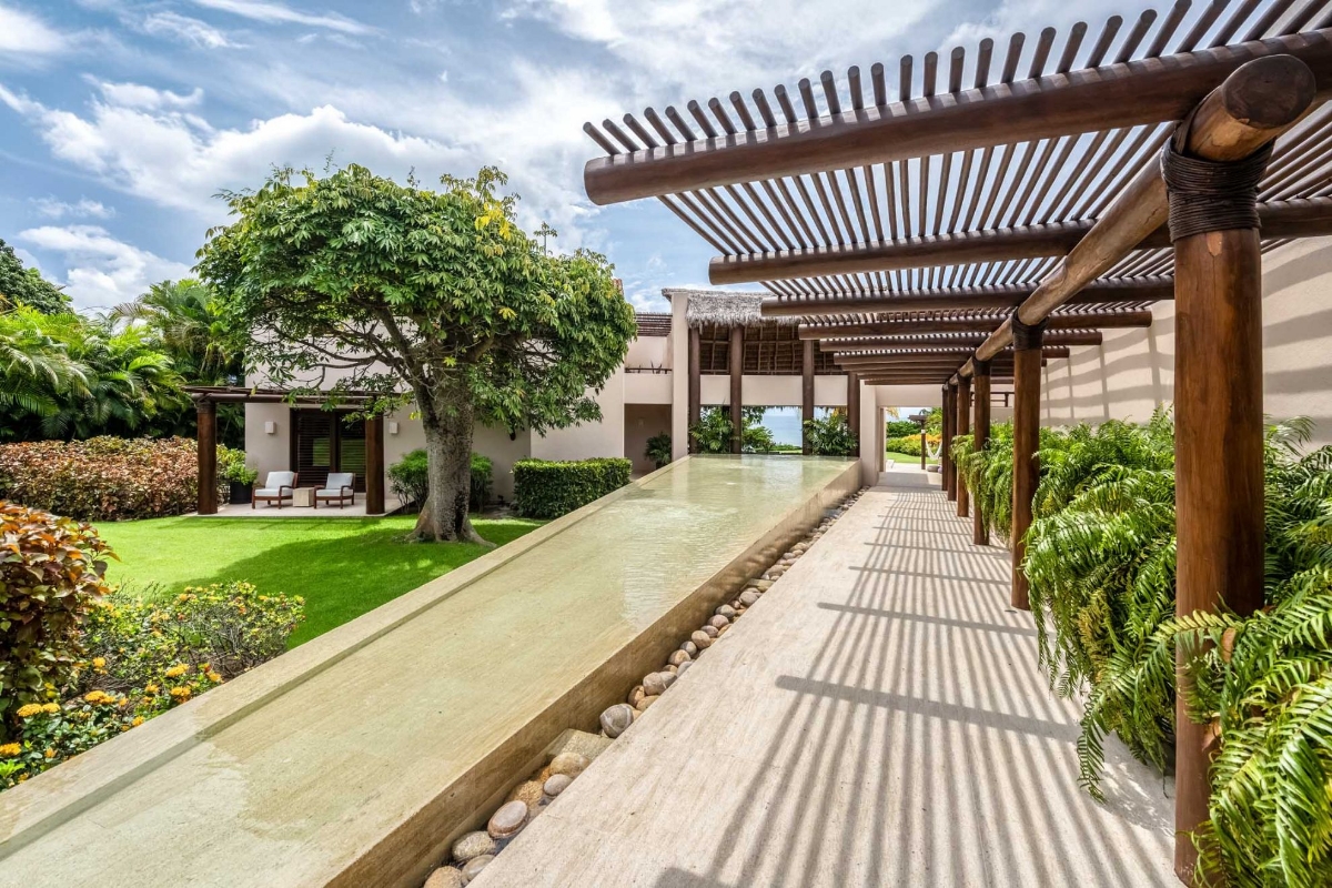 Outdoor walkway with wooden pergola and lush greenery at Casa Caída de Agua luxury villa