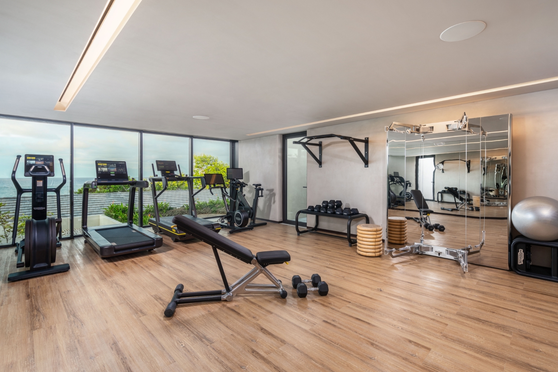 Fully equipped modern home gym at Bella Vils with premium cardio machines, free weights, and floor-to-ceiling windows