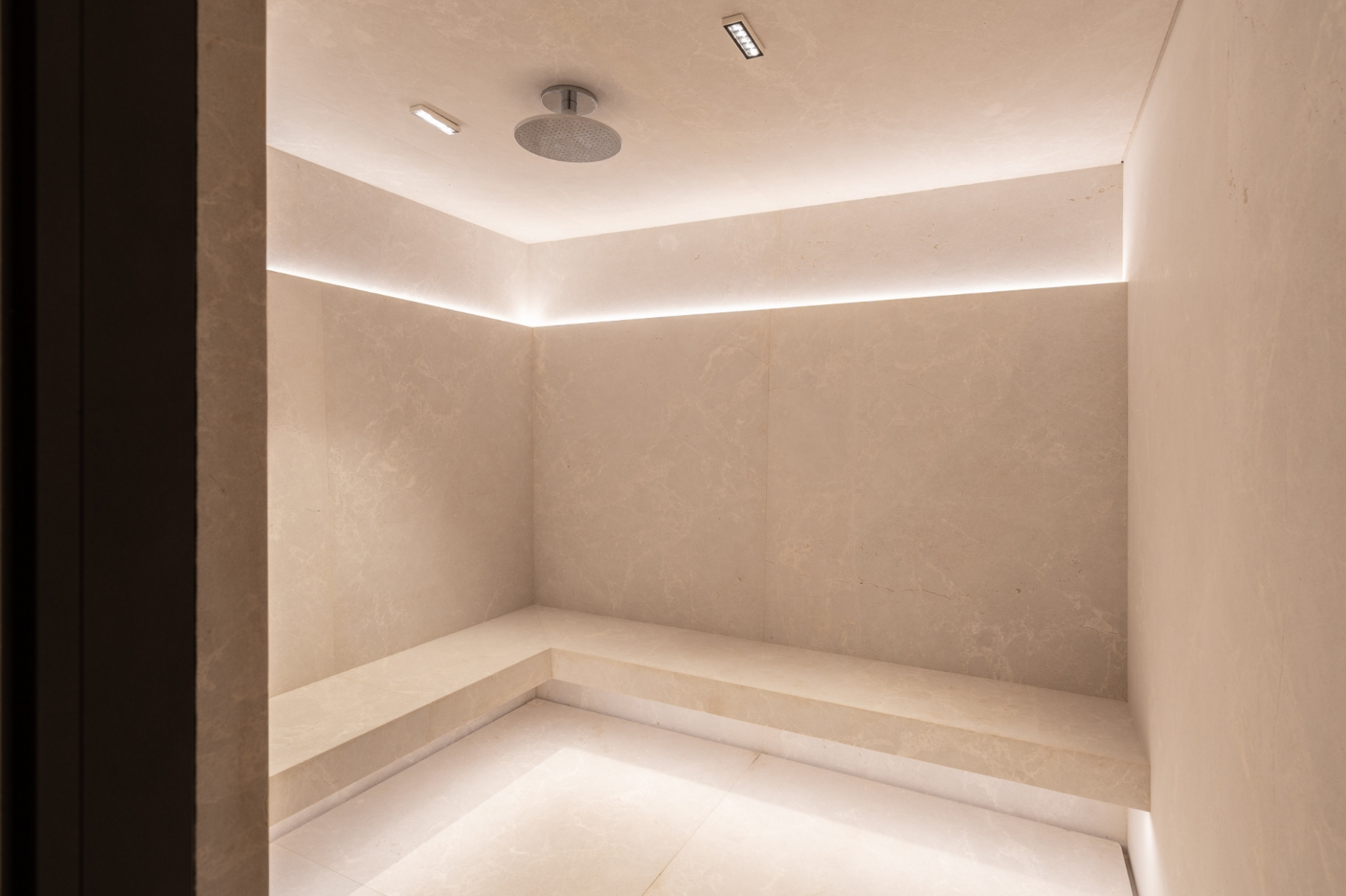 Modern luxury steam room at Bella Vils with minimalist stone finishes, ambient LED backlighting, and premium integrated seating